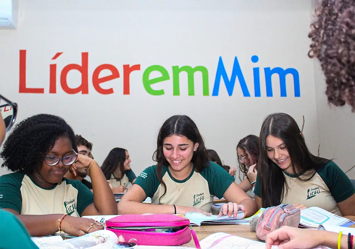Alunas estudando em grupo sob o painel do programa Líder em Mim