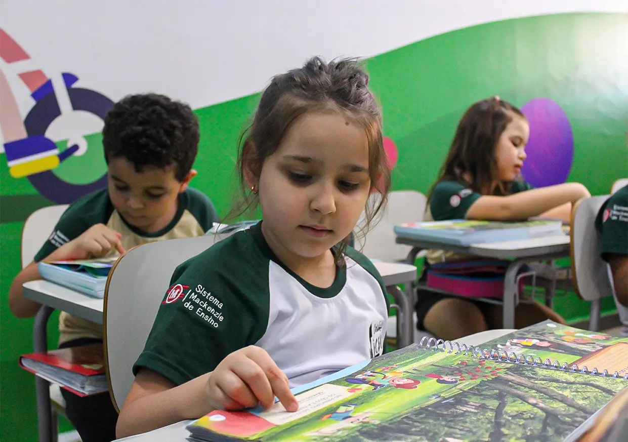 Alunos do Ensino Fundamental em sala de aula, folheando o material do Sistema Mackenzie de Ensino